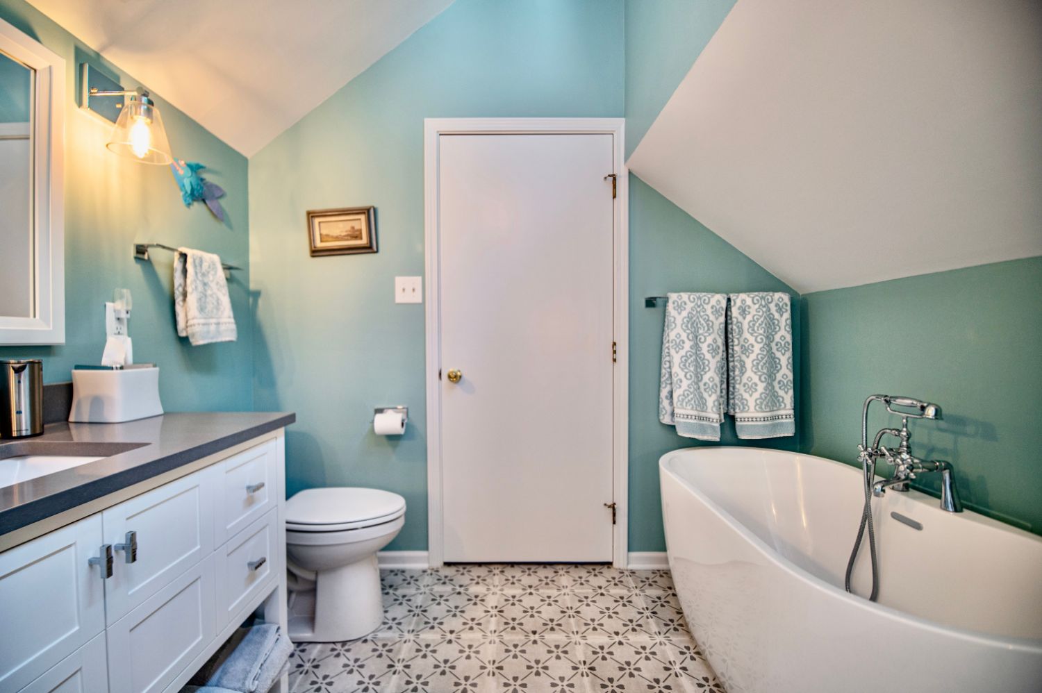 Remodeled bathroom with a freestanding soaking tub, white vanity and patterned floor tile