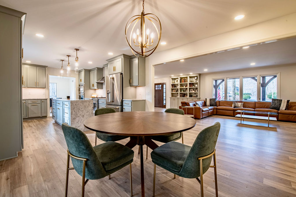 Remodeled open-plan kitchen in sage green cabinetry opening onto a dining area and family room