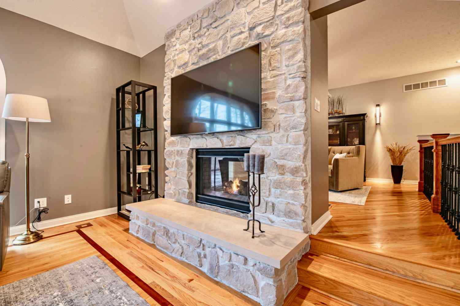 Remodeled great room with a floor-to-ceiling stone fireplace, hardwood flooring and vaulted ceiling