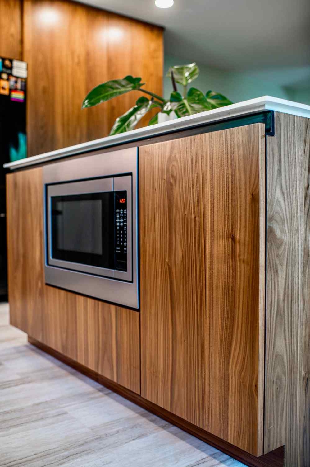 Walnut kitchen island with a built-in microwave and a waterfall countertop edge